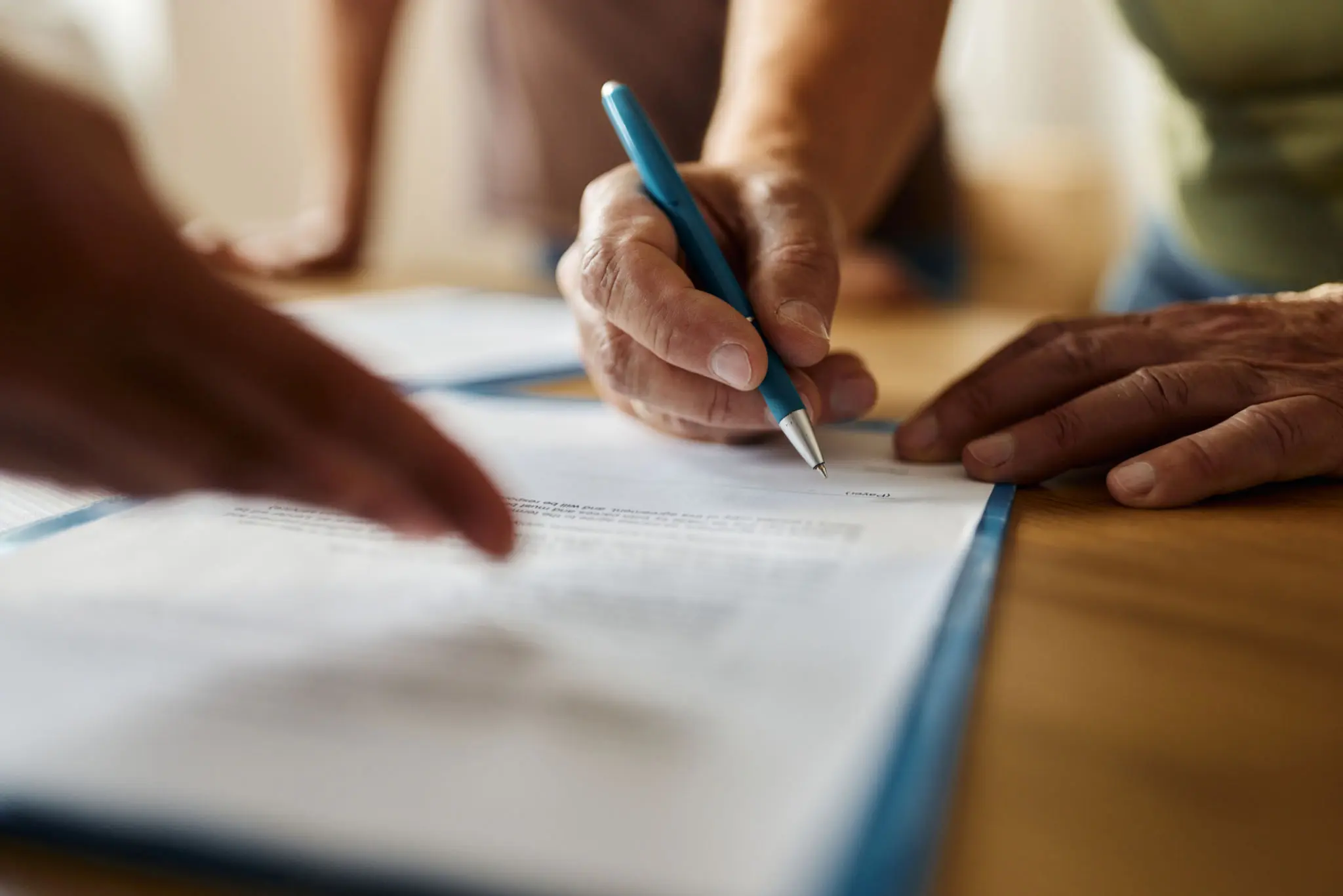 Hands signing a document with pen.
