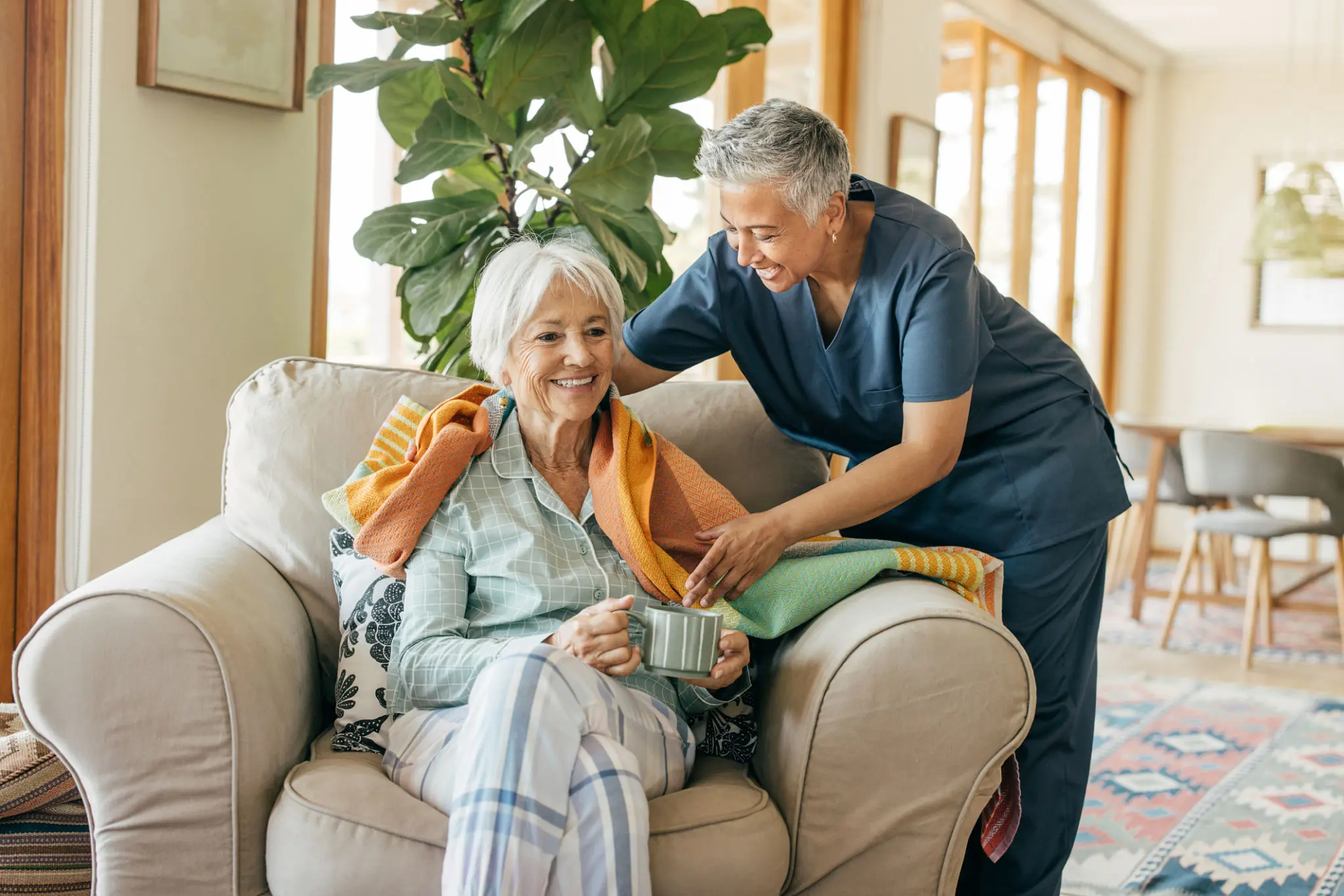 Elderly woman with caregiver in cozy room.
