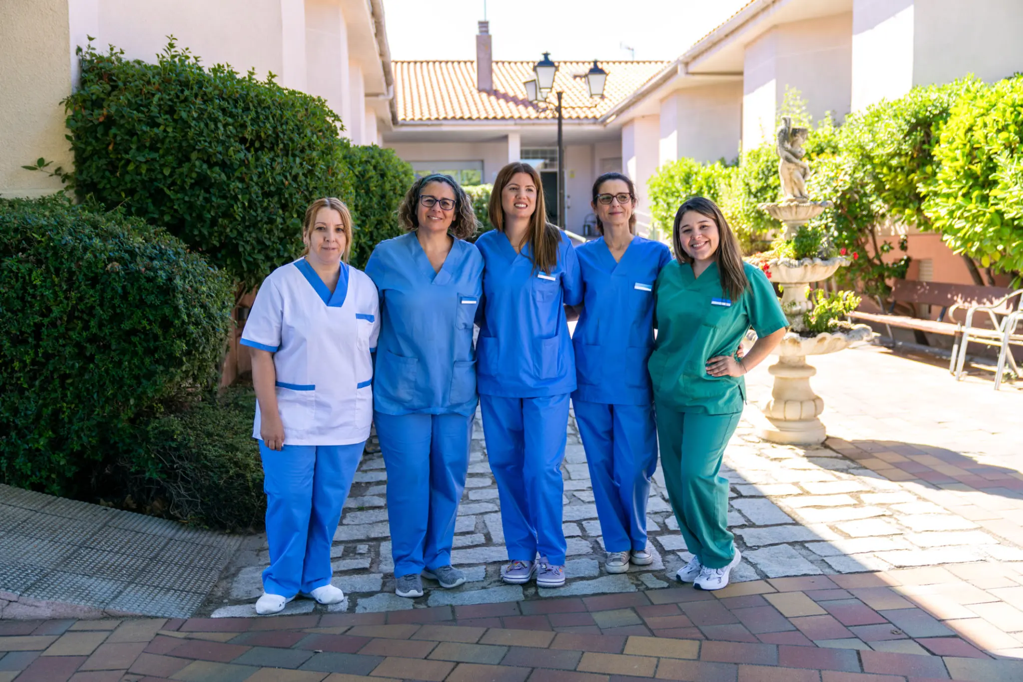 Five healthcare workers in colorful uniforms.
