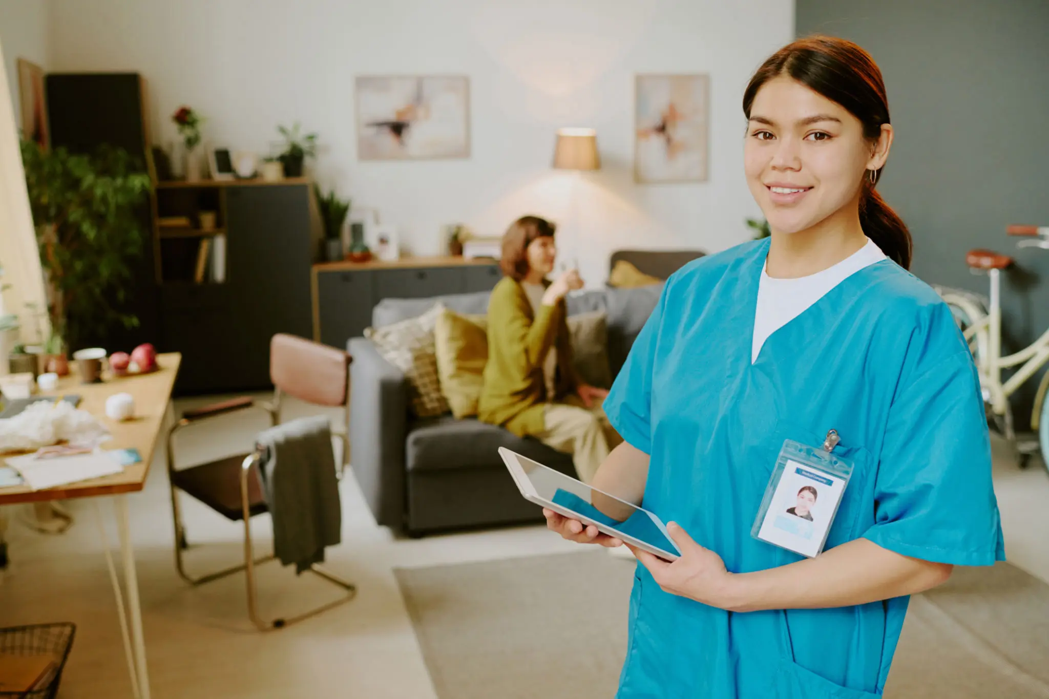 Healthcare professional with tablet in living room.